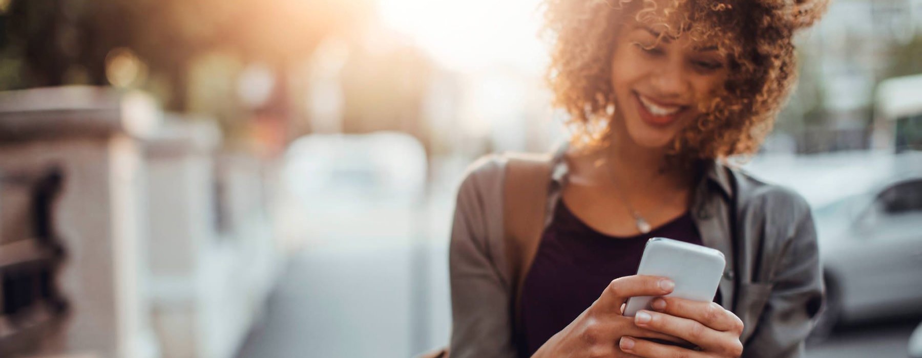 woman texts on her phone as she walks through the city